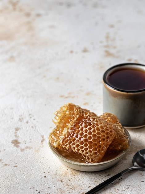 Honey in honeycombs in a saucer with tea and spoon text space