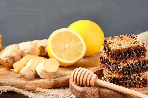 Honey in honeycombs on a wooden plate and honey with nuts with lemon and ginger in rustic style on a wooden table.