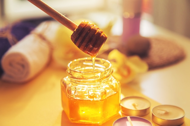 Honey is poured into the jar. Spa care concept. Natural home skin care. Blurred background. Beautiful light.