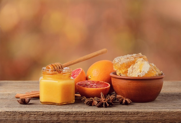 Honey in jar and honey combs in bowl with oranges and Badian on table healthy natural food concept