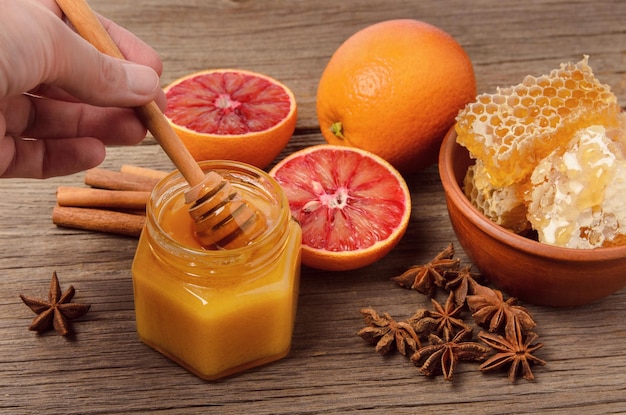 항아리에 꿀과 그릇에 꿀 빗, 오렌지와 바디안이 식탁에 있는 건강한 자연 식품 개념