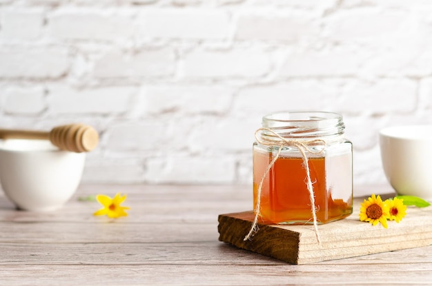 Honey in a jar a honey dipper and some marigolds