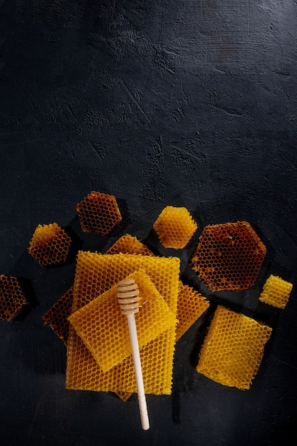 Honey in a jar and a honeycomb. On a black wooden background. Free space for text. Top view.