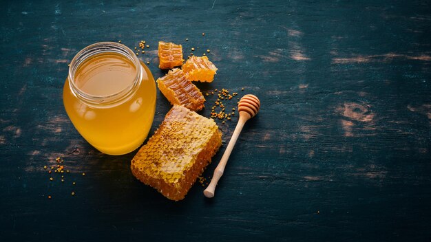 Honey in a jar and a honeycomb On a black wooden background Free space for text Top view