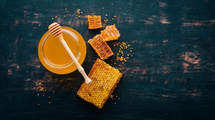 Honey in a jar and a honeycomb On a black wooden background Free space for text Top view