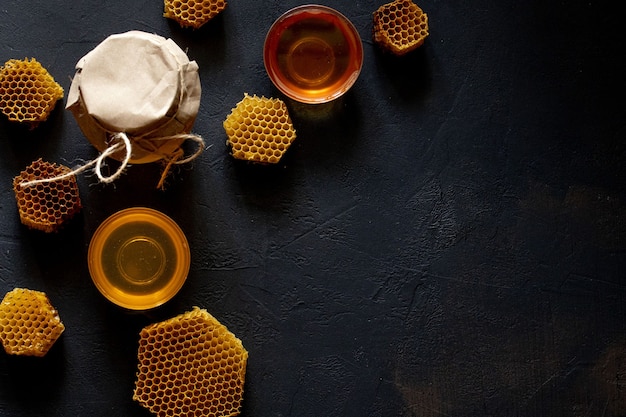 Honey in a jar and a honeycomb. On a black wooden background.Top view.