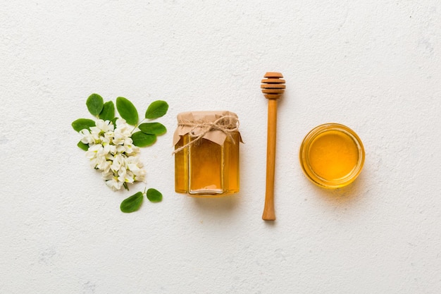 Honey jar with acacia flowers and leaves fresh honey top view flat lay