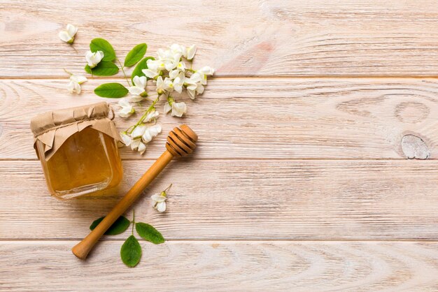 Honey jar with acacia flowers and leaves fresh honey top view flat lay