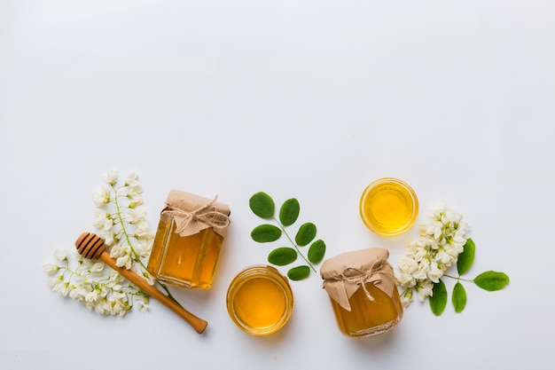 Honey jar with acacia flowers and leaves fresh honey top view flat lay