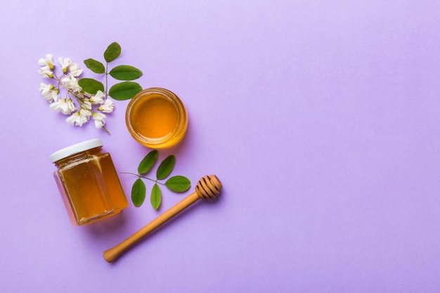 Honey jar with acacia flowers and leaves fresh honey top view flat lay