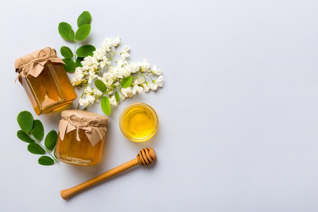 Honey jar with acacia flowers and leaves fresh honey top view flat lay