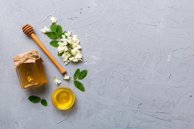 Honey jar with acacia flowers and leaves fresh honey top view flat lay