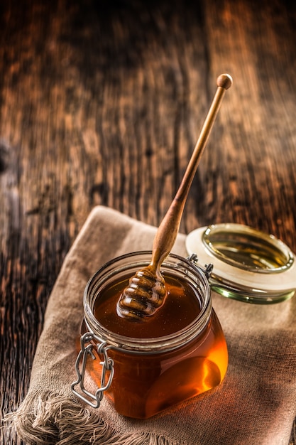 Honey jar with dipper on old woodn table.