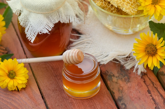 Honey in jar with honey dipper on rustic wooden table 