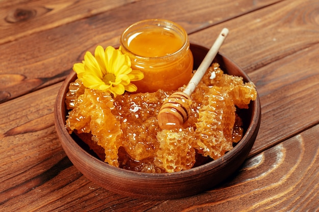 Honey in jar with honey dipper on vintage wooden background