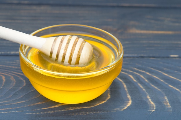 Honey in jar with honey dipper on wooden background