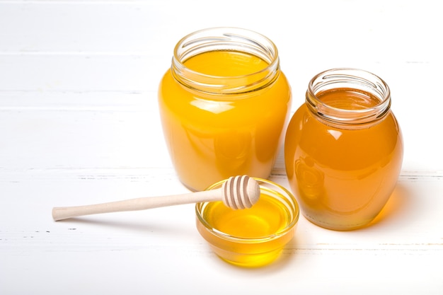 Honey in jar with honey dipper on wooden surface