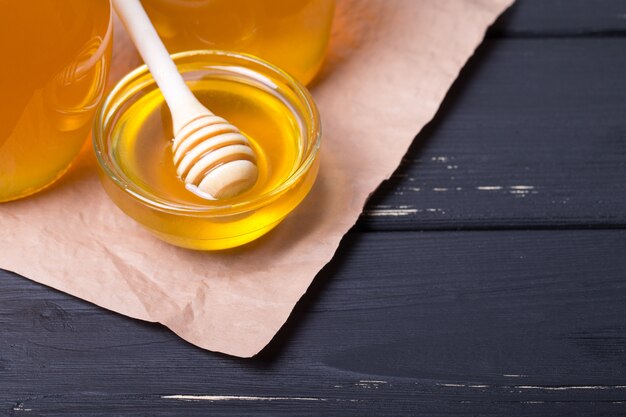 Honey in jar with honey dipper on wooden table