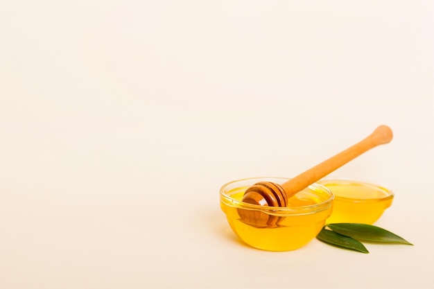 Honey in jar with leaves and honey dipper on colored background top view with copy text