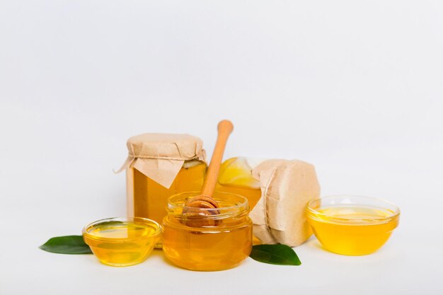 Honey in jar with leaves and honey dipper on colored background top view with copy text