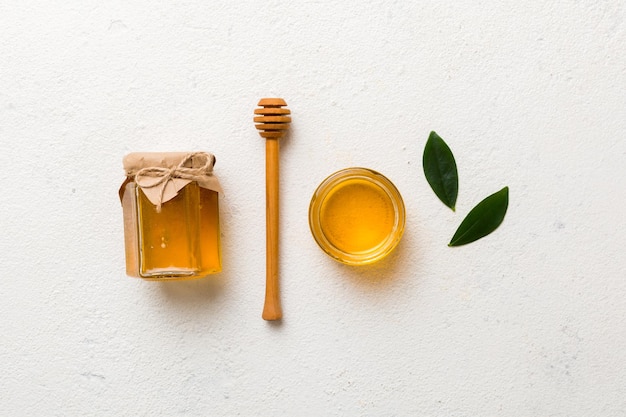 Honey jar with wooden honey dipper on white background top view with copy space Delicious honey bottle