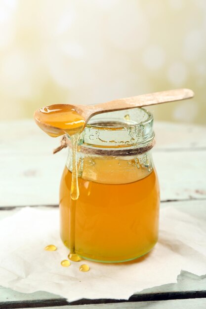 Honey jar with wooden spoon on light background