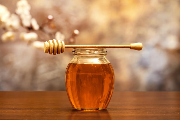 Honey jar on a wooden surface with a spring background