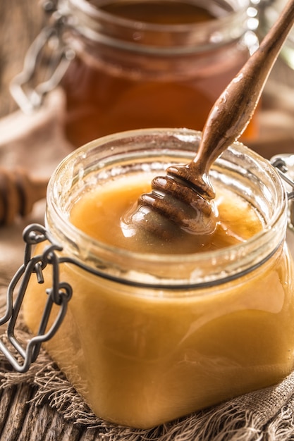 Honey in jars and  dipper on rustic oak table.