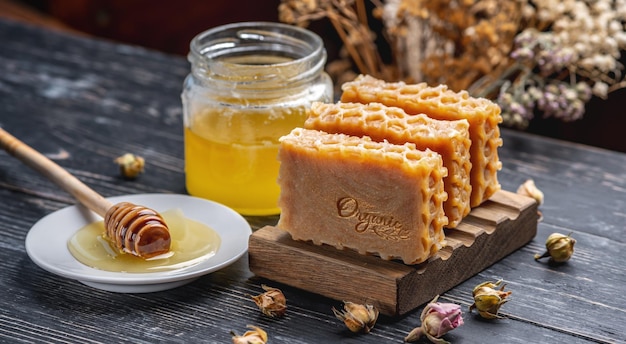 Honey natural handmade soap with the inscription Organic wooden soap dish jar of honey and honey stick on the table