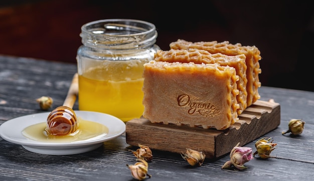 蜂蜜の碑文と自然な手作り石鹸蜂蜜とテーブルの上の蜂蜜棒の有機木製石鹸皿瓶