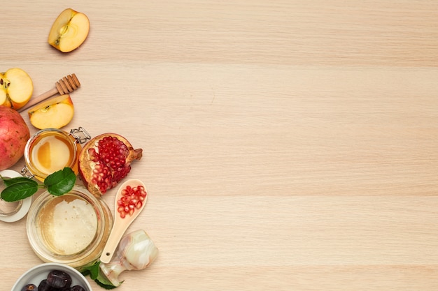 Honey, pomegranate, apple and dates on wooden board.