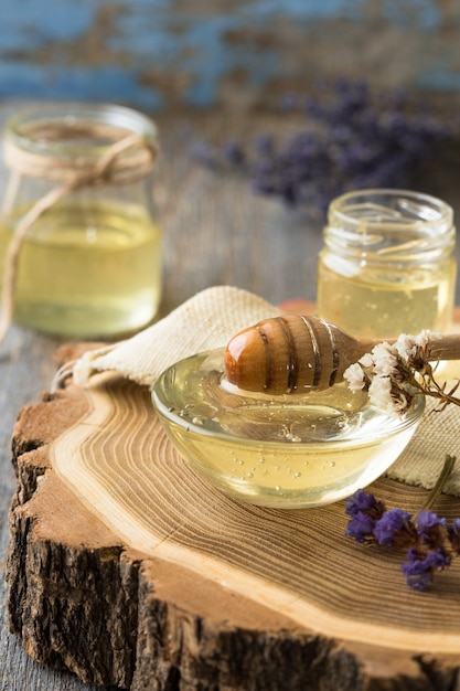 Honey pot, dipper, jar of fresh honey, honeycomb on a wooden table outdoors. Honey with honey dipper on wooden table