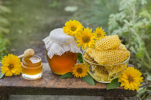 Honey pot dipper jar of fresh honey honeycomb on a wooden table outdoors Honey with honey dipper on wooden table