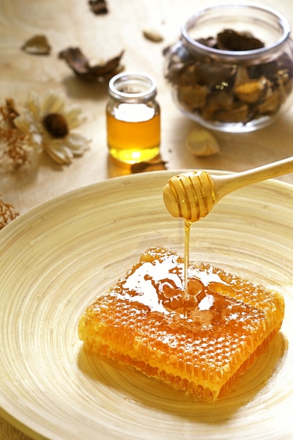 Photo honey pots with honeycomb on a wood table with flowers