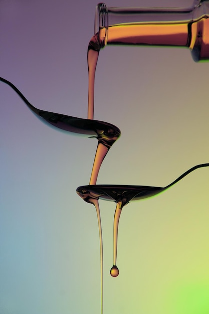 Photo honey pouring in spoons against colored background