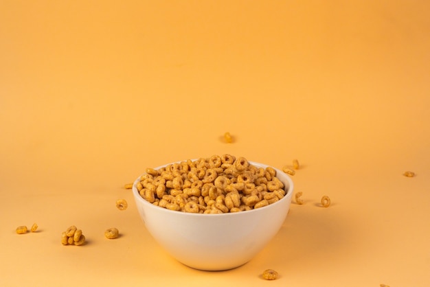 Scatola di cereali con anelli di miele per la colazione mattutina. fiocchi di mais che cadono nella ciotola bianca. movimento. copyspace.