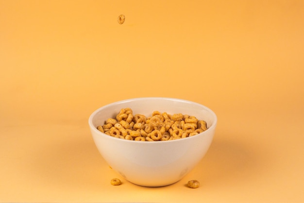 Honey rings cereal box for morning breakfast Corn flakes falling to the white bowl Motion Copyspace