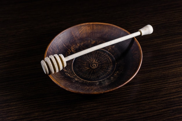 Honey spoon in the ceramic dish on dark wooden table