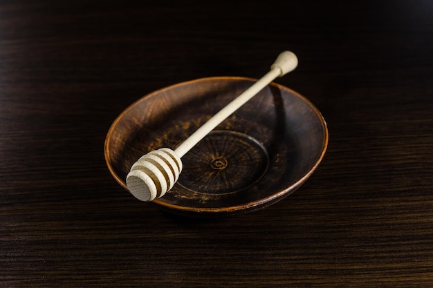 Photo honey spoon in the ceramic dish on dark wooden table
