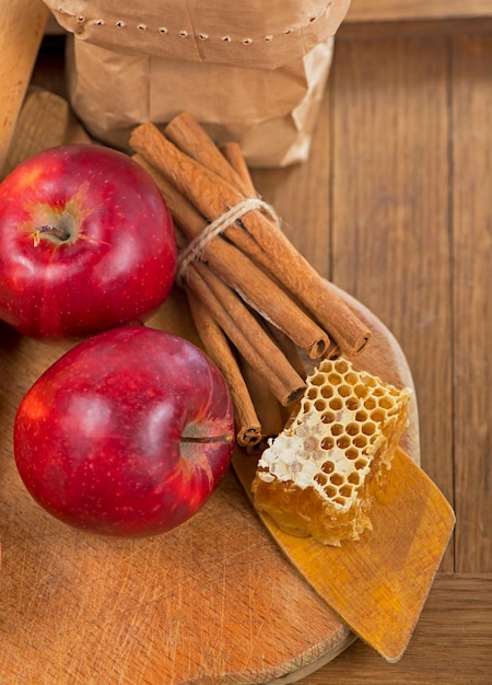 honey spoon, jar of honey, apples and cinnamon on a wooden background in a rustic style.