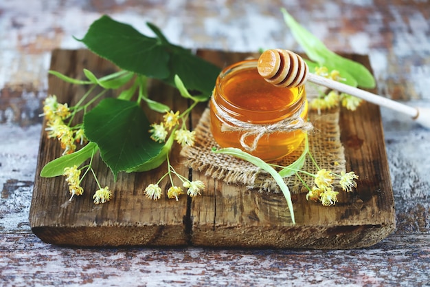 Honey stick, jar of linden honey, linden flowers.