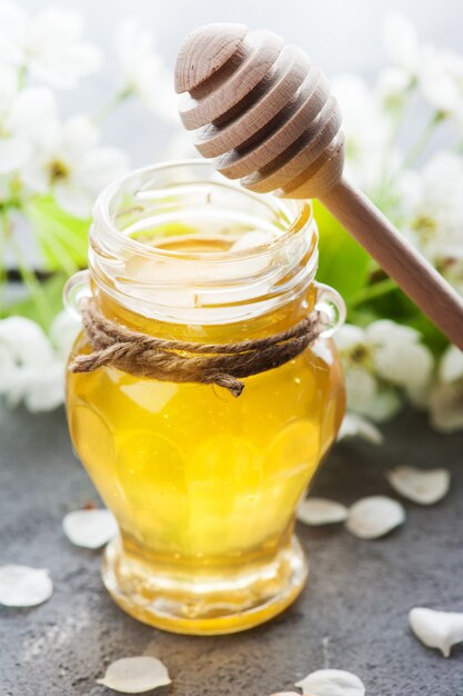 Honey with blossoms and wooden spoons