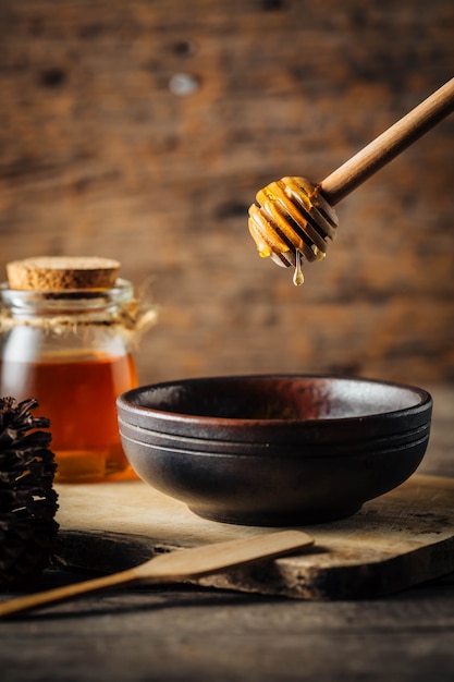 honey with dipper on wooden background