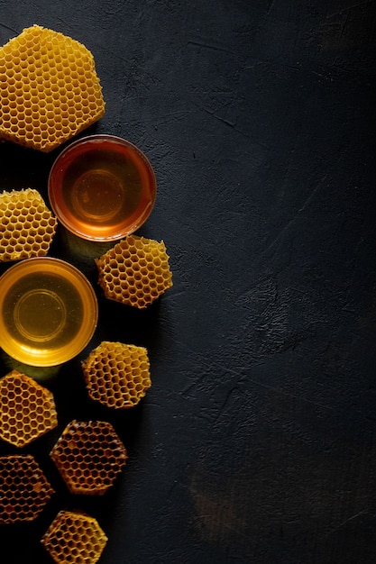 Honey with honeycomb on black table, top view. space for text.