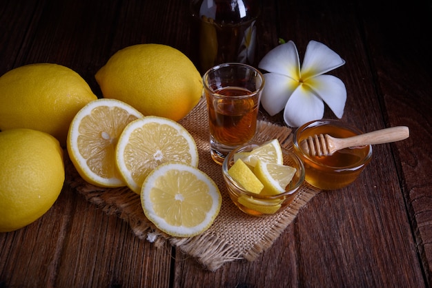 Honey with lemons on wooden table.