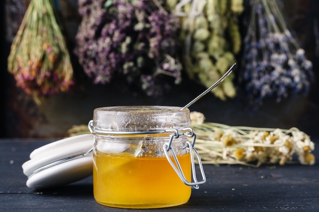 Honey with tea on rustic table backgound with herbs