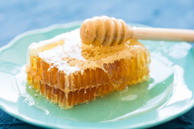 Honey with wooden honey dipper and honeycombs, close-up