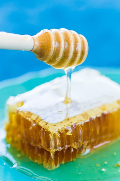 Honey with wooden honey dipper and honeycombs, close-up