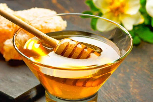 Honey with wooden honey dipper on wooden table