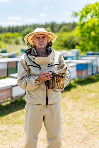 Honey worker in apiary with smoker Beekeeping smoker in hands